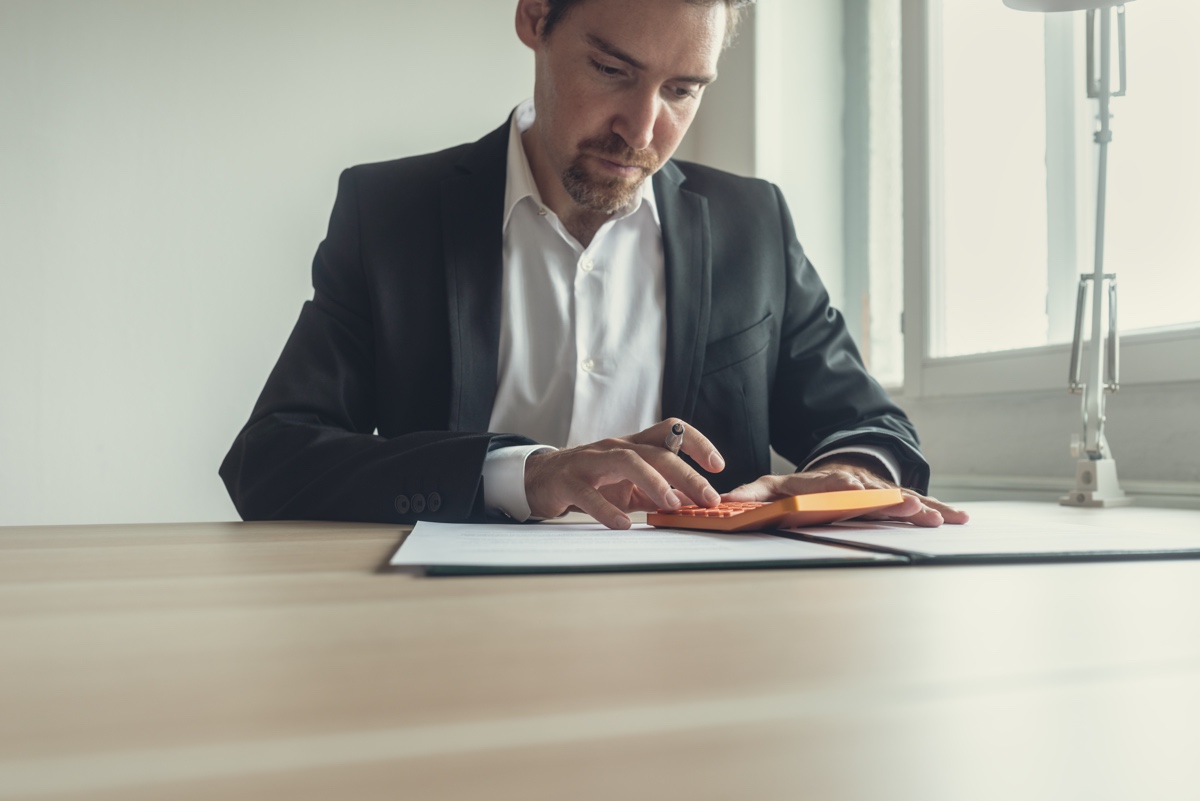 Businessman at office desk using calculator